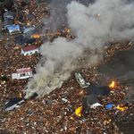 Flames rise from houses and debris half submerged in tsunami in Sendai, Miyagi Prefecture (state) after Japan was struck by a strong earthquake off its northeastern coast Friday, March 11, 2011.